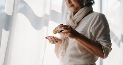 Focused mature lady examining drug prescription label at home.  holding bottle with pills in hands, reading instruction to medicine.