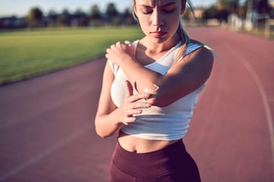 Female Putting Ointment On Injured Elbow Before Training